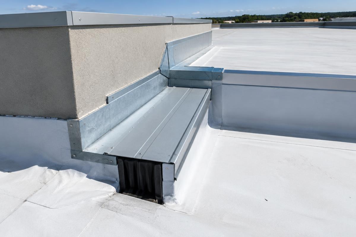 Metal expansion joint cover and flashing where an existing commercial roof meets a higher new addition roof at a parapet